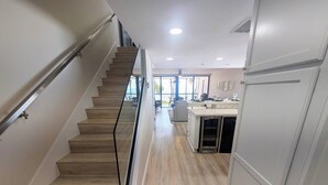 Una escalera que lleva a una sala de estar con cocina y comedor.