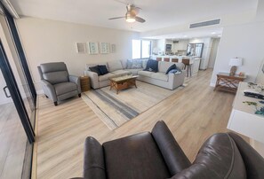 Uma sala de estar moderna com sofá, poltronas, mesa de centro e um espaço de jantar com luminária.