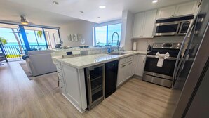 Una cocina moderna con una isla grande, electrodomésticos de acero inoxidable y vistas al exterior.
