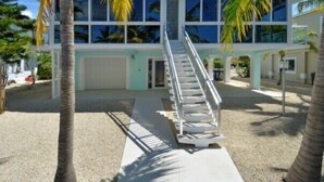 Un bâtiment moderne à deux étages, doté d’un escalier central, de grandes fenêtres et d’une façade aux couleurs claires.