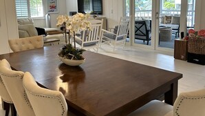 A spacious dining area with a large wooden table and cream-colored upholstered chairs. - Beautiful updated stilted home makes for a super getaway. (Key Largo)