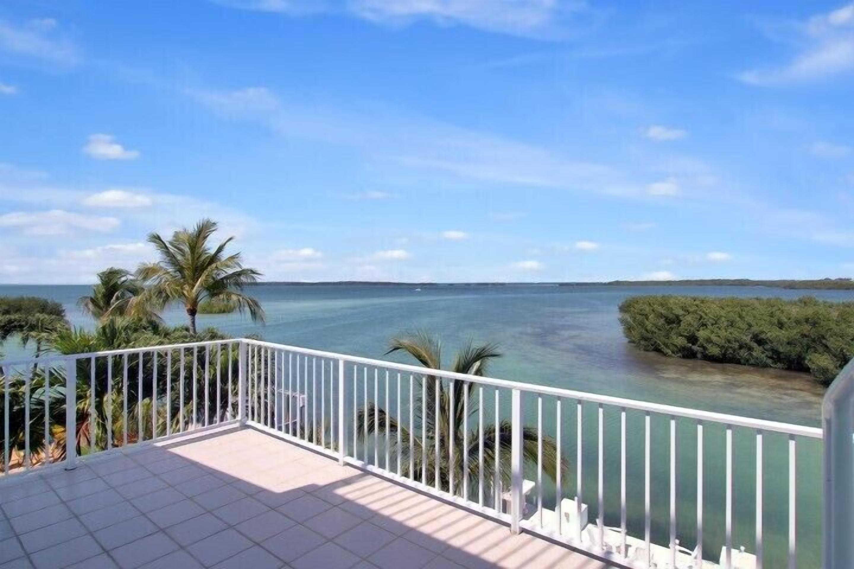 A balcony with a view of the sea and a small island.