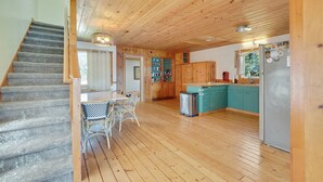 A wooden interior with a staircase, a dining area with a table and chairs, and a kitchen with cabinets and a refrigerator. - Loons Landing - Relax on the lake, your perfect Traverse City retreat. (Traverse City)