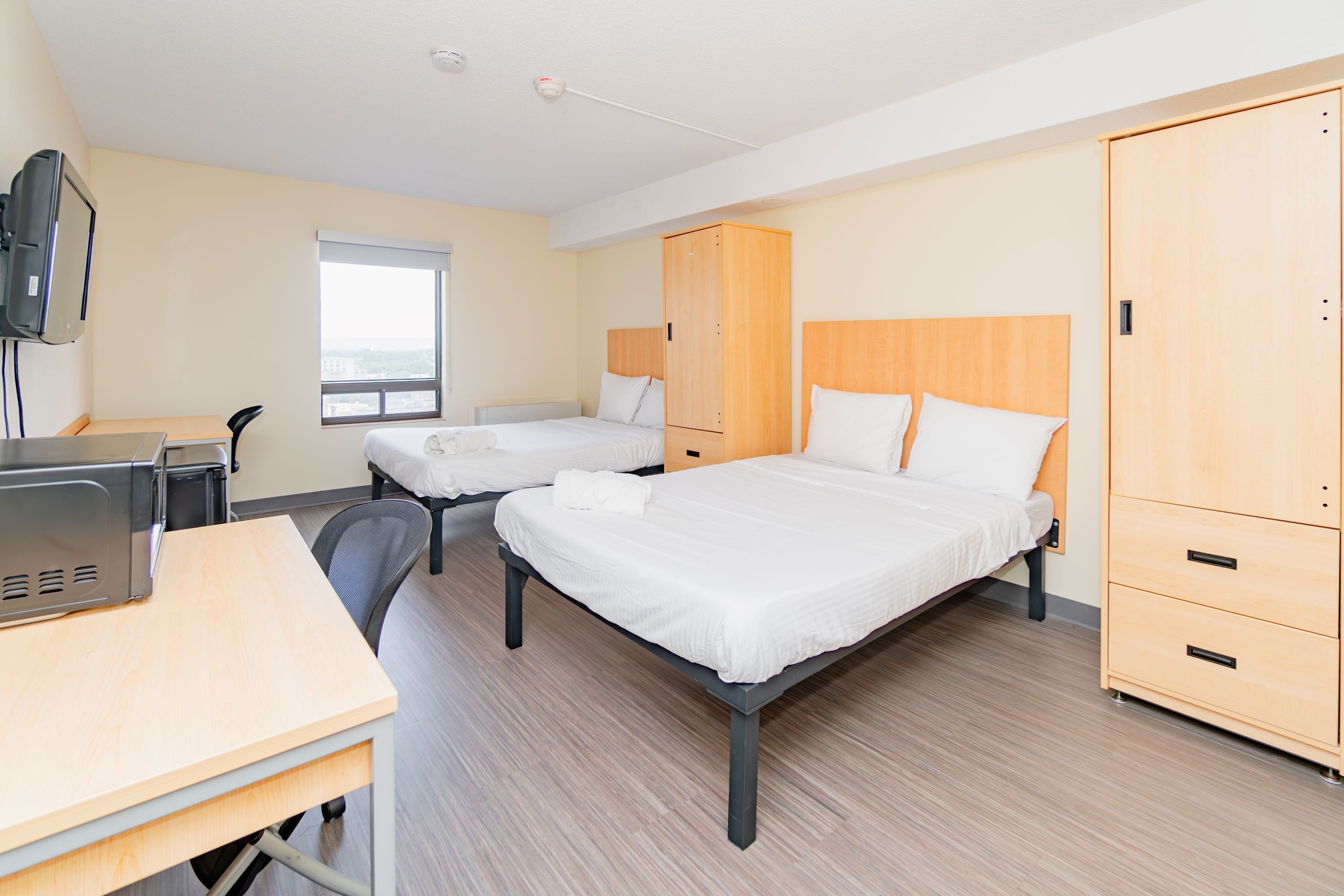 A hotel room with two beds, a desk, a TV, and a wardrobe.