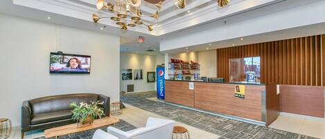 A lobby with a reception desk, seating area, and a television screen.