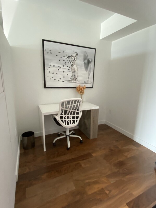 A small, white desk with a white chair and a framed picture of a leopard on the wall. - Downtown luxury 1 bedroom wifi and laundry across arenas (Winnipeg)
