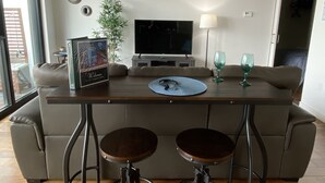 A modern living room with a large flat-screen TV, two bar stools, a coffee table, and a sofa. - Downtown luxury 1 bedroom sleeps 3 wifi and laundry  (Winnipeg)