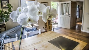 Ein Essbereich mit Holztisch und Stühlen, einem Blumentopf und einer Tür zu einem anderen Raum.