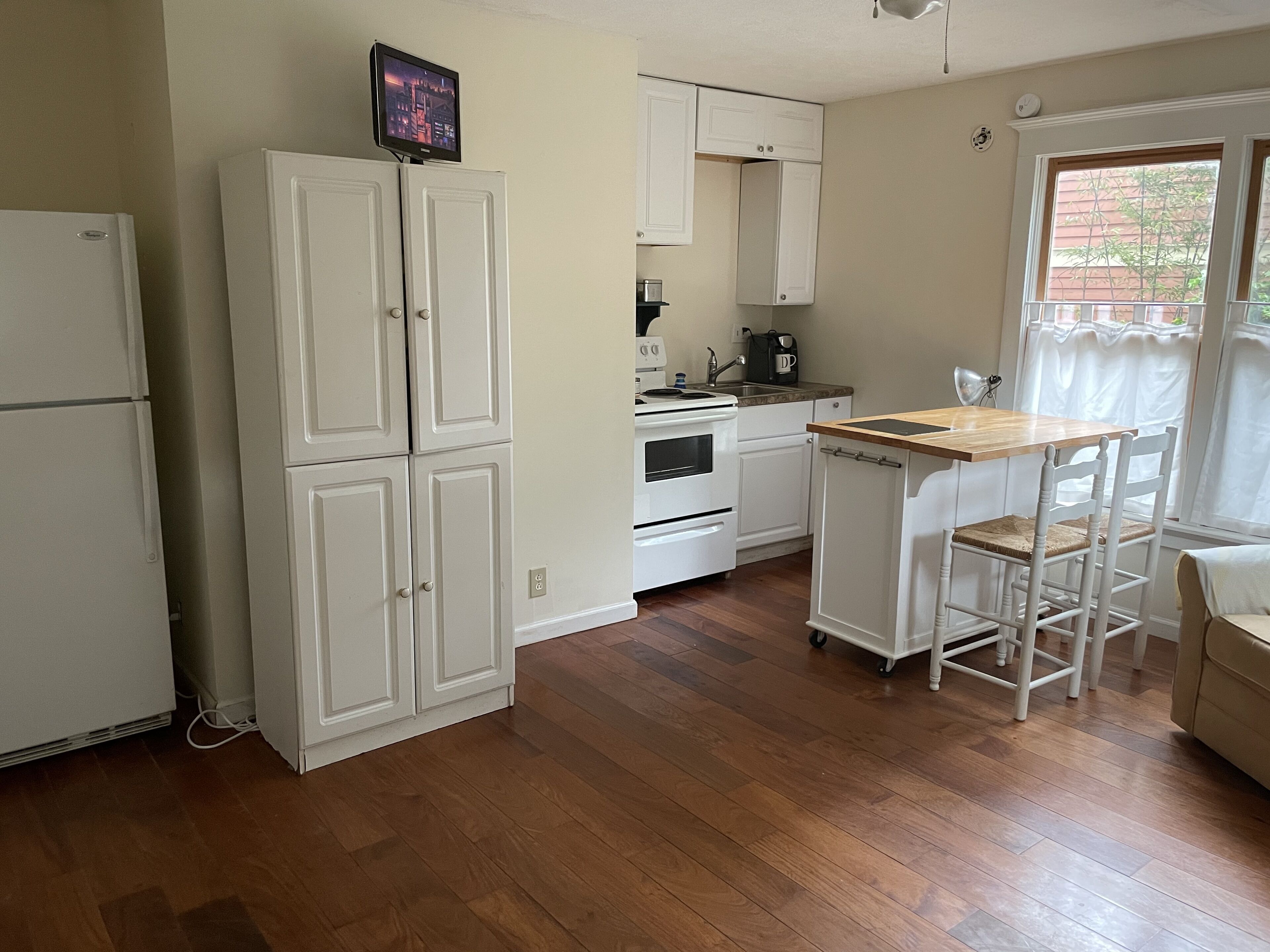 Una cocina con armarios blancos, una mesa de comedor de madera y un horno empotrado.