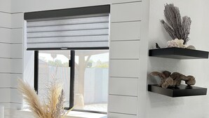 A modern kitchen with a window, a vase with dried plants, and decorative shelves.