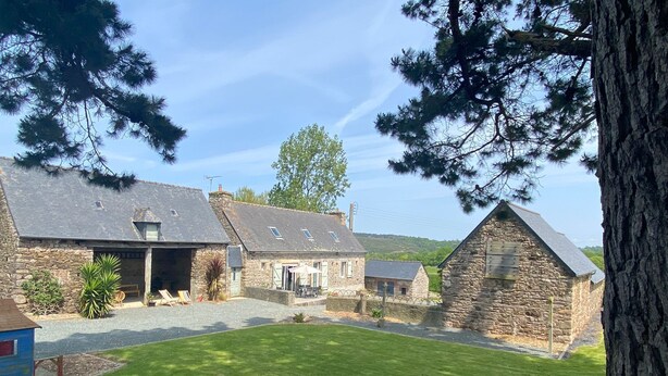 A stone building with a grassy yard and a tree. - Maison AU Calme (Ploëzal)