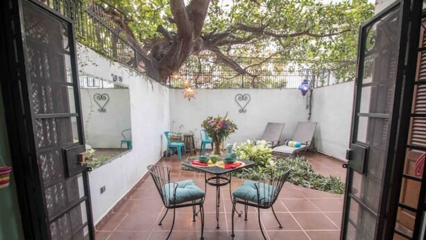 An open patio with a dining table and chairs, surrounded by a white wall and a tree. - Mexican flair One Bedroom (Puerto Vallarta)