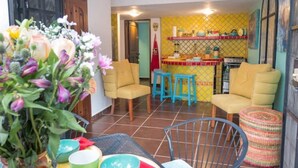 A cozy living room with yellow armchairs, a dining table with blue stools, and a kitchen area with yellow tiles and red accents. - Mexican flair One Bedroom (Puerto Vallarta)
