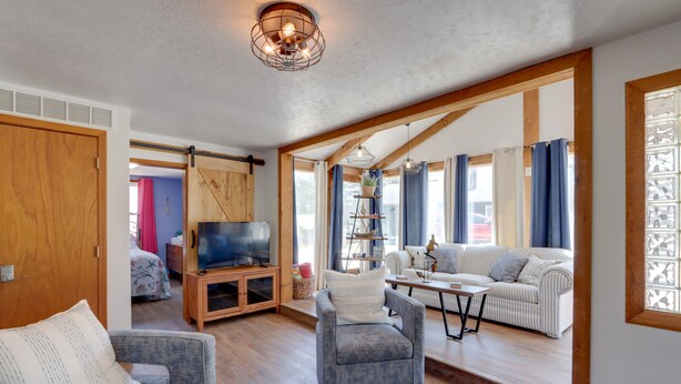 Ein geräumiges Wohnzimmer mit Holzbalkendecke, einem Fernseher, einer Couch und einem Couchtisch.