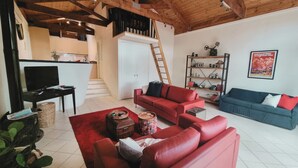 Un salon avec des canapés rouges, un téléviseur, un escalier et une bibliothèque.