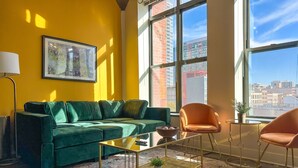 Un salon moderne avec un canapé vert, une table basse et un fauteuil orange.