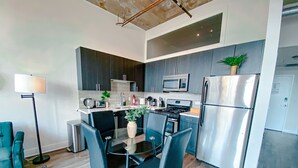 A modern kitchen with dark cabinetry, stainless steel appliances, and a glass dining table with black chairs.