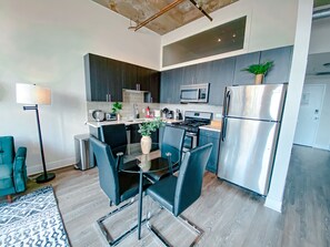 A modern kitchen with dark cabinetry, stainless steel appliances, and a glass dining table with black chairs. - McCormick Place city view 2br/2ba with optional parking for up to 8 guests (Chicago)