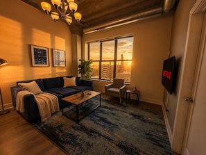 A living room with a sofa, coffee table, and a TV mounted on the wall.