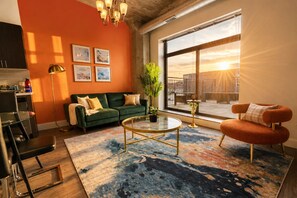 A modern living room with a green sofa, a round coffee table, and a large window with a city view.