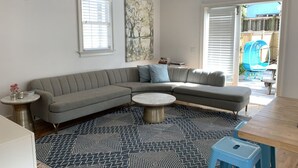 A modern living room with a grey sectional sofa, a round coffee table, and a patterned rug. - 5 Queen Beds, Downtown, Park in Private Driveway, Stroll to Charleston's Best (Charleston)