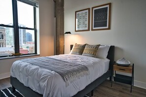 Ein Schlafzimmer mit einem großen Bett, einem Nachttisch mit einer Schale und zwei gerahmten Bildern an der Wand.