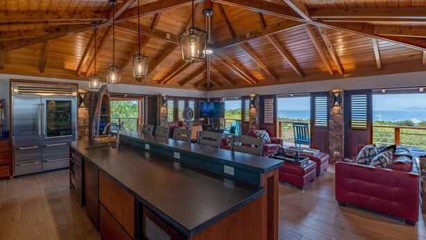 Cozinha espaçosa com uma ilha grande, vigas de madeira no teto e vista para o exterior.
