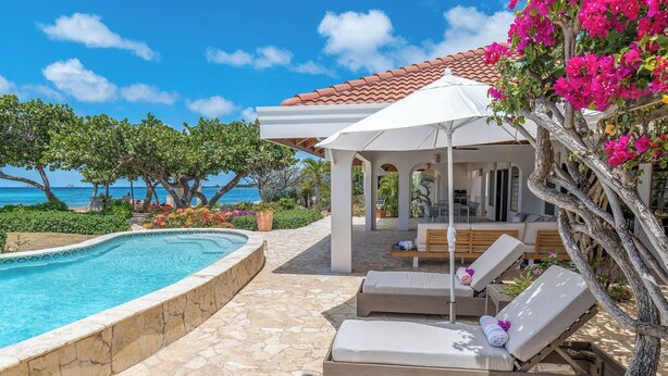 A poolside area with lounge chairs and a pergola, overlooking a body of water. - Sea Palms Villa - Holiday in Luxury in this Stunning Rental Villa (Mahoe Bay)