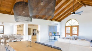 A spacious living area with a wooden dining table, a sofa, and a ceiling fan. - Sea Palms Villa - Holiday in Luxury in this Stunning Rental Villa (Mahoe Bay)