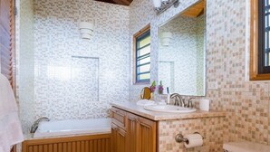 A bathroom with a bathtub, wooden vanity, sink, and toilet. - Sea Palms Villa - Holiday in Luxury in this Stunning Rental Villa (Mahoe Bay)