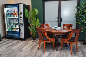 A wooden table with four chairs, a vending machine with a 'COLD drinks' sign, and two large potted plants. - McCormick Place Studio with optional parking for up to 4 guests (Chicago)
