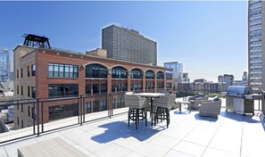 Enjoy dining and socializing on this rooftop terrace with a city view, featuring a barbecue grill and comfortable seating.