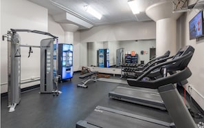 Un gimnasio con cintas de correr, máquinas de pesas y un dispensador de agua.