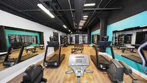 Une salle de sport équipée de tapis de course, de vélos elliptiques et de matériel de musculation.