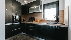 Une cuisine moderne avec des meubles de couleur noire, un four encastré, un four à micro-ondes et un plan de travail en bois.