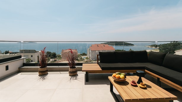 Une terrasse sur le toit avec un canapé, une table en bois et un pot de fleurs.