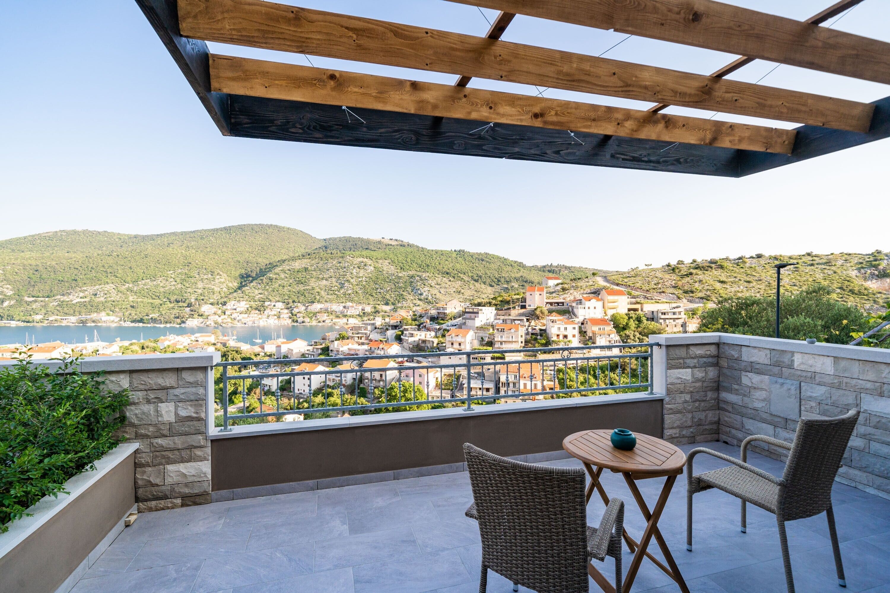 Een balkon met rieten stoelen en een tafel met uitzicht op een kustplaats.
