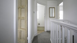 A hallway with a wooden door, a mirror, and a carpeted staircase. - Port Sunlight, Duke of York Cottage, Grade 2 Listed (wirral)