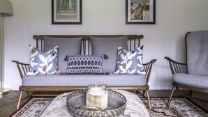 A cozy living room with a wooden bench, patterned cushions, and a decorative tray with a candle. - Port Sunlight, Duke of York Cottage, Grade 2 Listed (wirral)