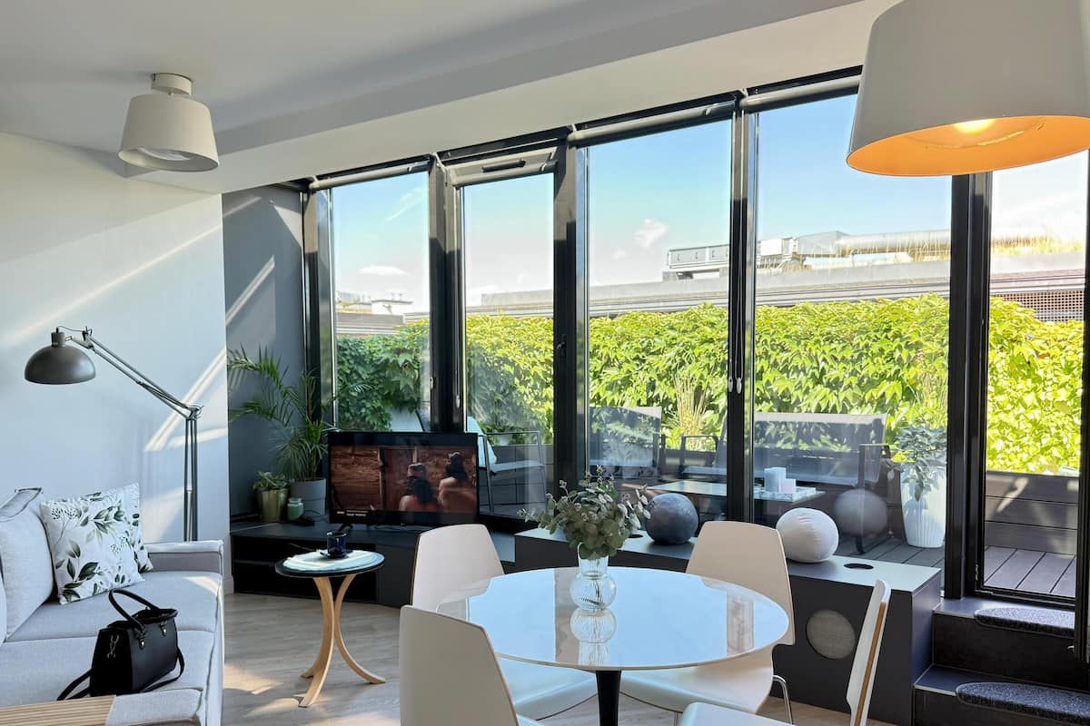 A modern living room with a large window, a round table, and a sofa.