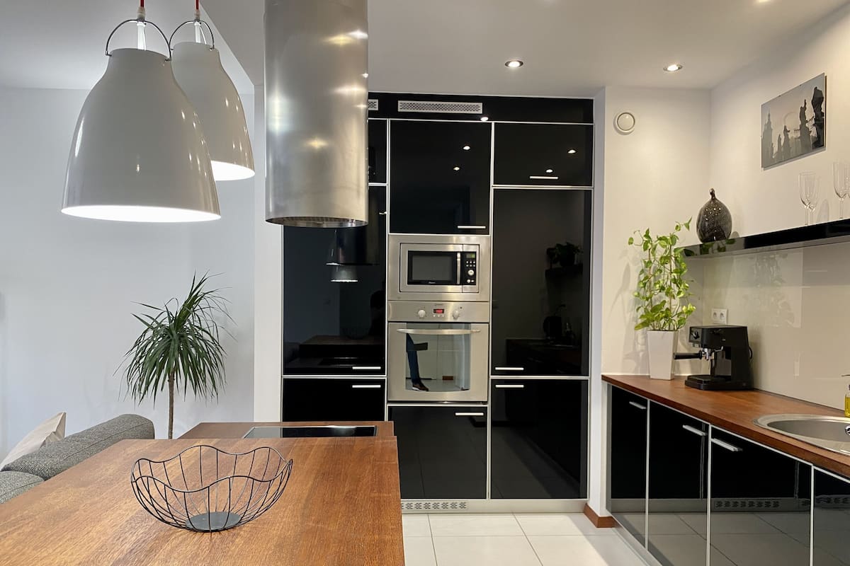 A modern kitchen with black cabinets, stainless steel appliances, and a wooden dining table.