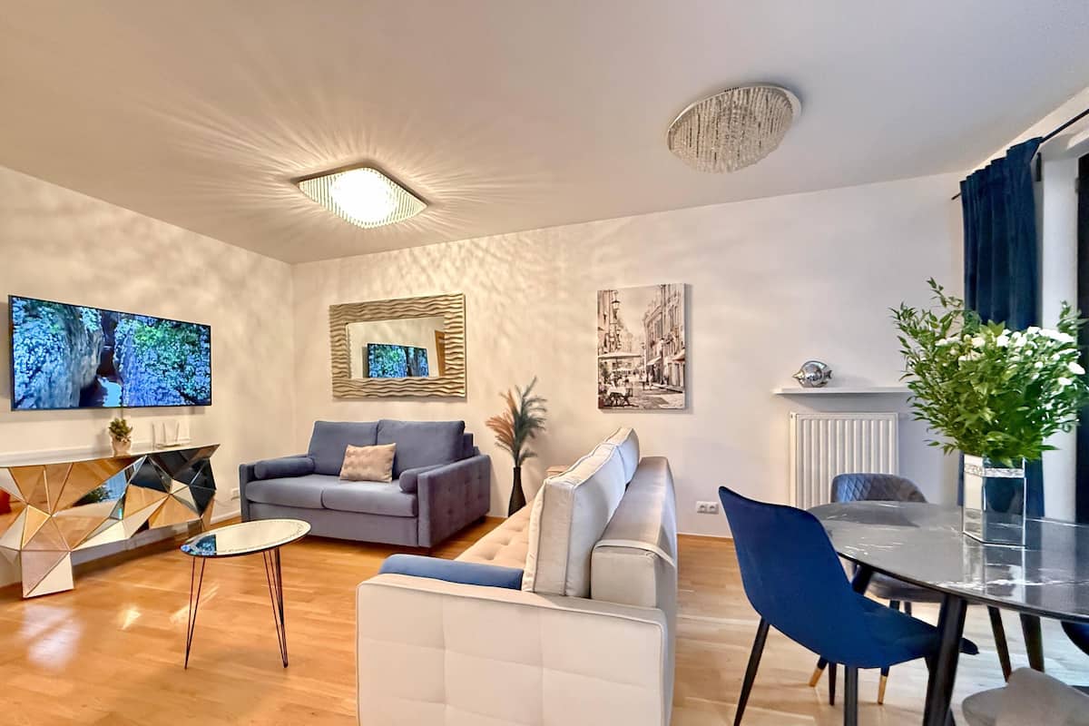 A modern living room with a sofa, a dining table, and a TV.