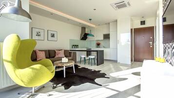 A modern living room with a yellow chair, a sofa with patterned cushions, a coffee table, and a black and white rug.