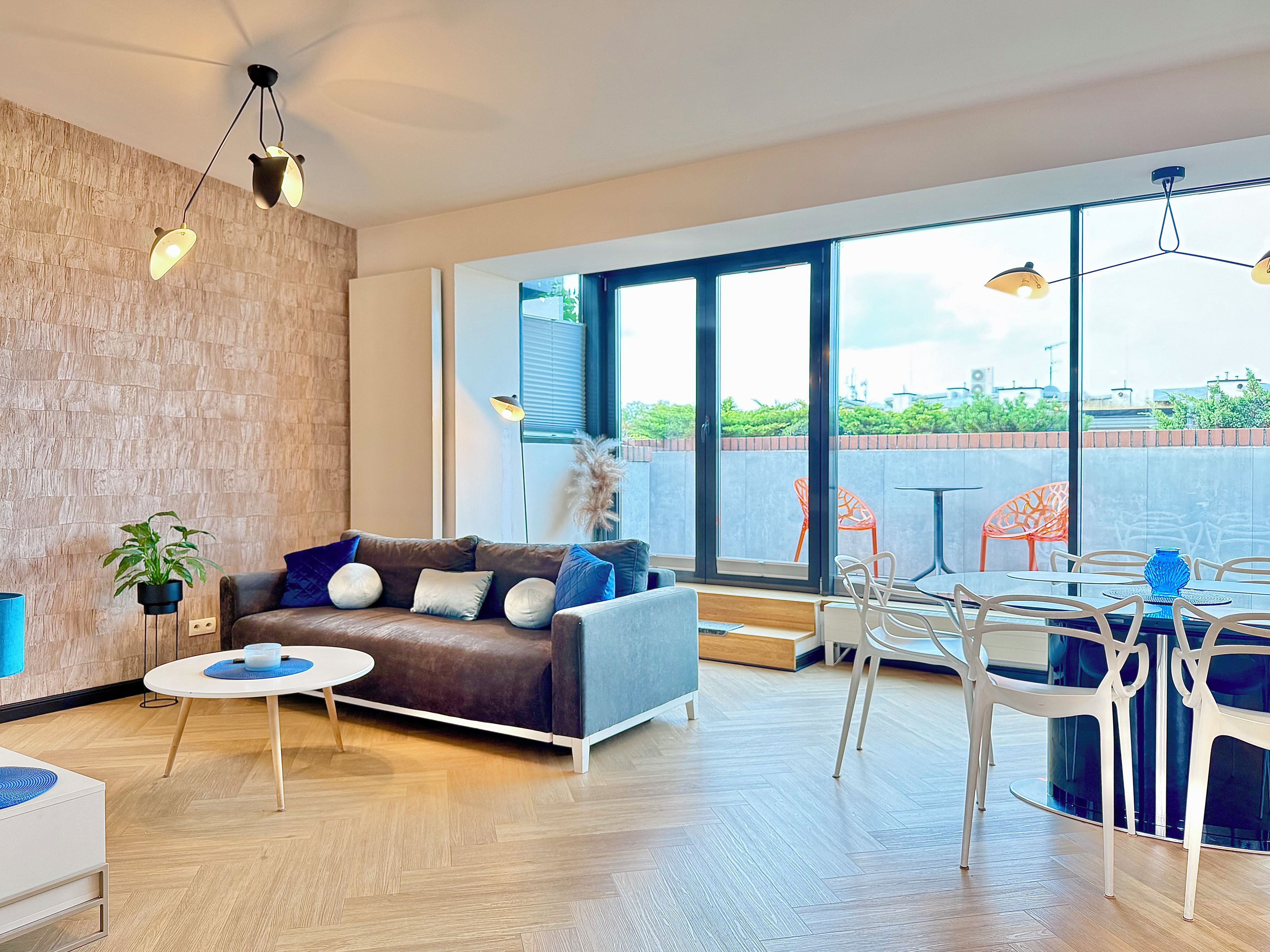 A modern living room with a sofa, coffee table, and dining area with chairs.