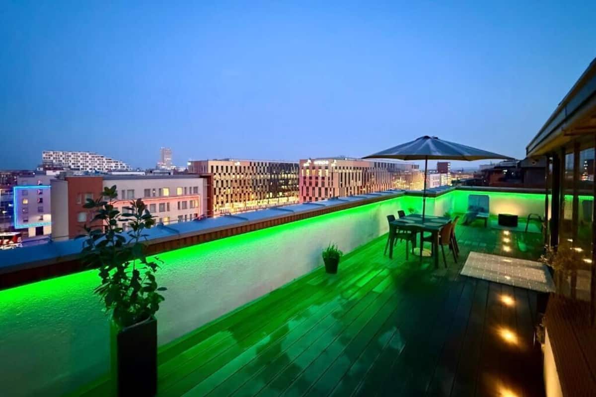 A rooftop bar with a view of the city skyline, a pool, and outdoor seating.