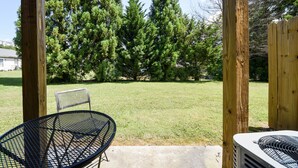 A patio area with a metal table and chairs, surrounded by wooden posts and a string of lights.