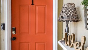 A bright orange door with a number 1, a doormat, a lamp, and a 'welcome' sign.