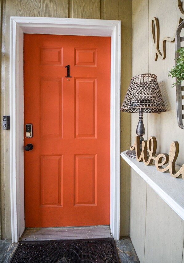 A bright orange door with a number 1, a doormat, a lamp, and a 'welcome' sign. - Eclectic Abode I-75 Hop & Skip City BEST LOCATION (Cleveland)