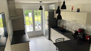 Una cocina moderna con encimera negra, una mesa de comedor y vistas a un patio con mobiliario exterior.