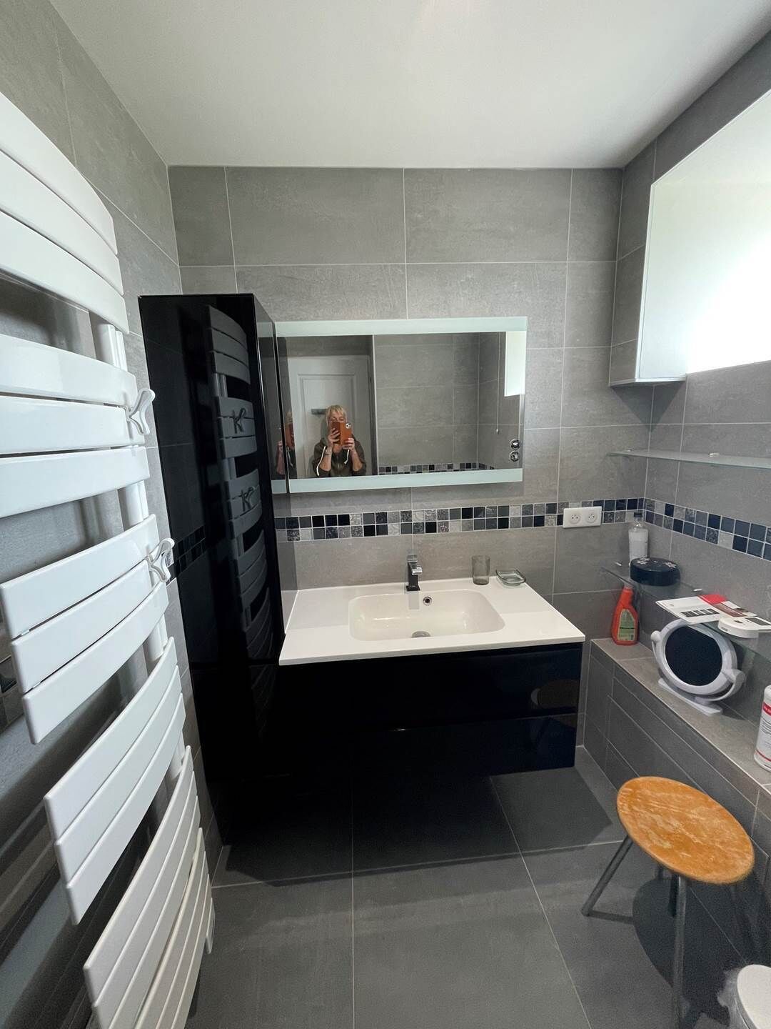 A modern bathroom with a white sink, a mirror, and a towel rack.